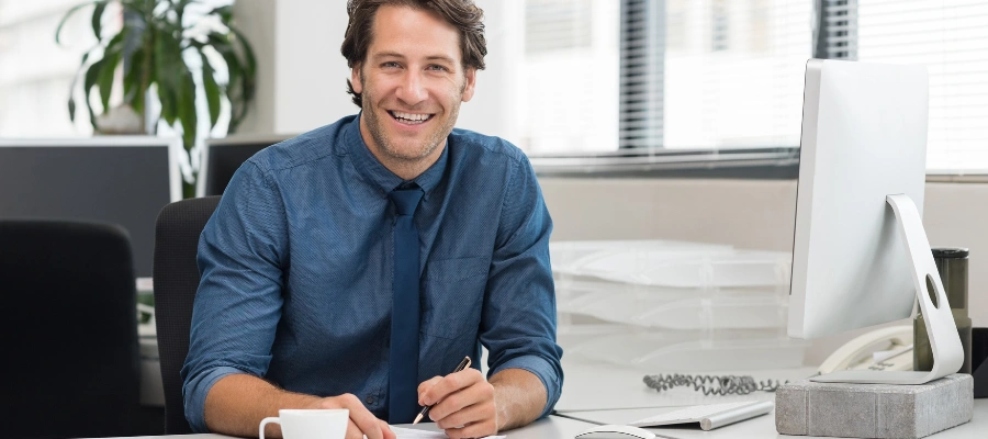 businessman behind desk with computer and paperwork