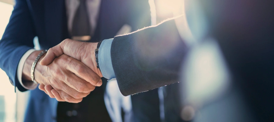 business professionals talk at table over papers and laptop
